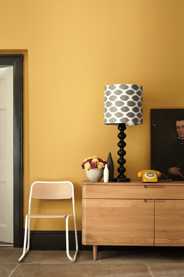 Hallway painted in mustard yellow (Yellow-Pink) with a wooden side table and chair.