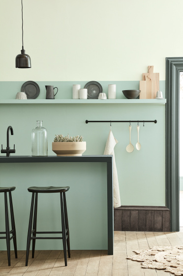 Kitchen space in varying shades of Aquamarine with a breakfast bar and stools on a wooden floor.