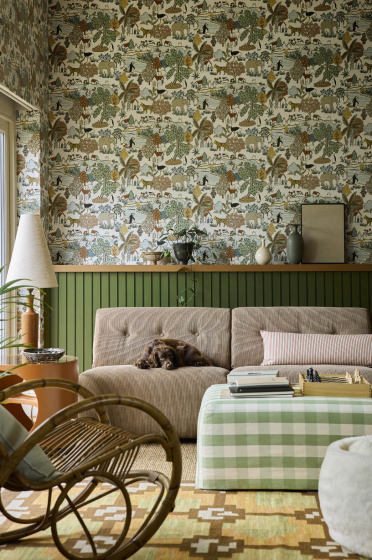 Living space featuring green wildlife print wallpaper (Animal Kingdom - Pea) with green paneling behind a sofa, foot stool and a rocking chair.