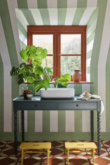 Bathroom featuring light green and white striped wallpaper (Broad Stripe- Pea Green) with a basin underneath a window.