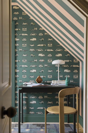 Home office space featuring car print wallpaper (Road Trip - Pleat) on the back wall and striped wallpaper on the right (Broad Stripe - Pleat) with a desk and chair.