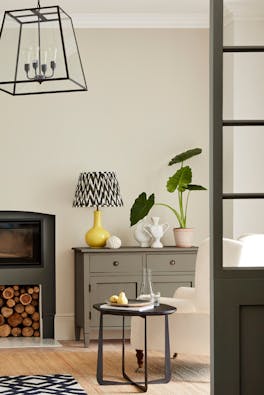 Neutral living space painted in 'Portland Stone' with grey drawers, fireplace and an armchair.