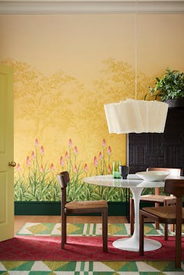 Dining room with yellow mural wallpaper (Upper Brook Street - Soleil) and a dining room table with wooden chairs.