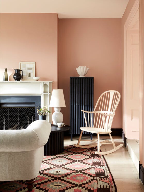 Pale pink living room in varying shades of Masquerade, alongside a rocking chair, sofa and Aztec rug.