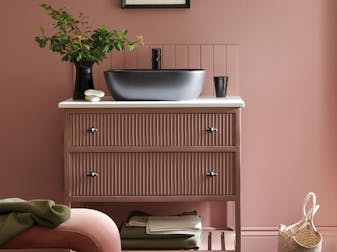 Bathroom sink area painted in blush pink shade 'Hellebore'  with darker pink 'Blush' on the vanity unit and a black sink.