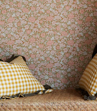 Reading nook featuring ditsy floral wallpaper (Spring Flowers - Bombolone) with shelving surround and a seat with scatter cushions.