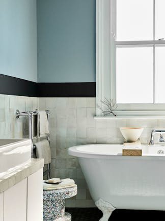 Bathroom with pale blue (Bone China Blue) upper walls and white tiles underneath, next to bathtub, window and sink.