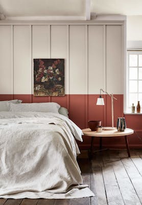 Bedroom with a light grey (French Grey) upper wall and a terracotta red 'Tuscan Red' lower wall behind a bed.