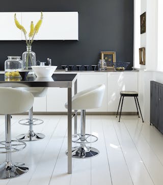 Rich black (Lamp Black) kitchen with bright white units and stools next to a black table.