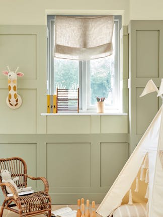 Children's nursery painted in 3 different shades of green neutral 'Green Stone' with children's toys and a small wicker chair.