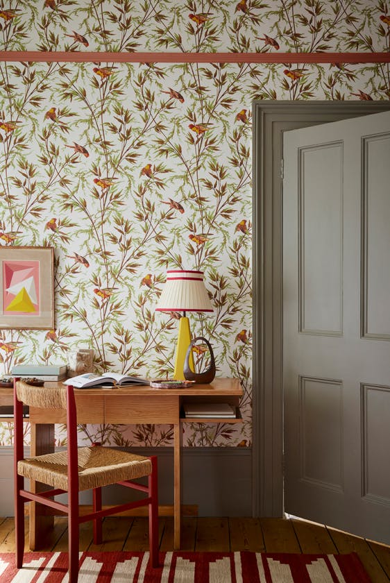 Home study space featuring bird and leaf wallpaper (Great Ormond St - Galette) with a grey door, wooden desk and chair.