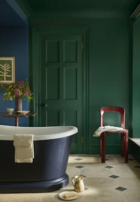 Bathroom painted in rich green shade 'Mid Azure Green' with a deep blue bathtub and vibrant blue 'Deep Space Blue' on the left hand wall.