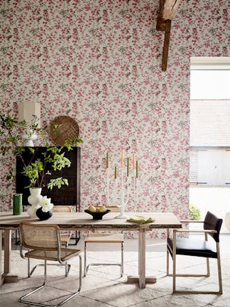 Dining room with pink printed floral and bird wallpaper (Massingberd Blossom - Mineral) and wooden dining table and chairs.