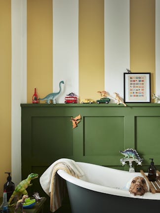 Yellow (Yellow-Pink) and white (Silent White) striped bathroom walls with deep green (Hopper) panelling and bathtub with a dog sat inside.