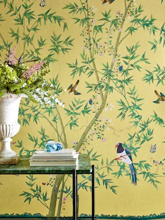 Home study with a bright yellow floral and bird wallpaper (Belton Scenic - Sunbeam) with a glass desk placed in front.