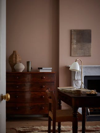 Bedroom painted in muted pink shade 'Split Pink' with a double bed next to a wooden sidetable.