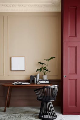 Warm neutral (Castell Pink) home study area with a red (Arras) door next to a wooden desk and chair. 