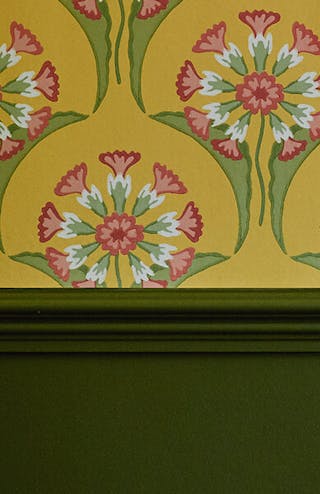 Close-up of bright yellow floral wallpaper (Hencroft - Punch) alongside dark green (Jewel Beetle) dado rail and blue jug.