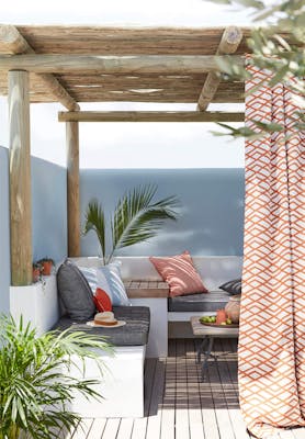 Outside lounge area with a corner seating area with the wall painted in pale blue (Bone China Blue) underneath a wooden roof.