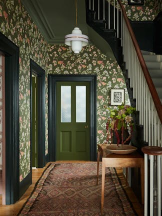 High ceiling hallway featuring dark green floral wallpaper (Aderyn - Olive Colour) with dark green woodwork and a tapestry rug.