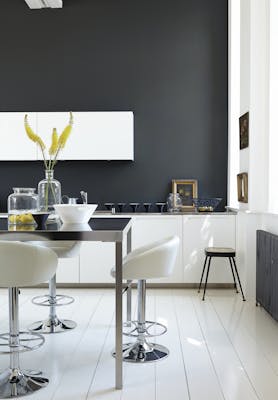 Rich black (Lamp Black) kitchen with bright white units and stools next to a black table.