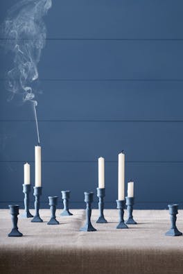 Paneled wall painted in muted indigo blue (Woad) with matching candle holders and white candle sticks.