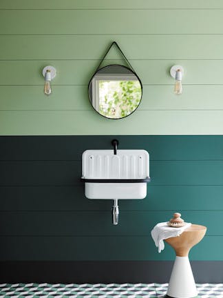 Paneled bathroom with the upper wall painted in Aquamarine and lower wall in dark green with a white sink and round mirror.