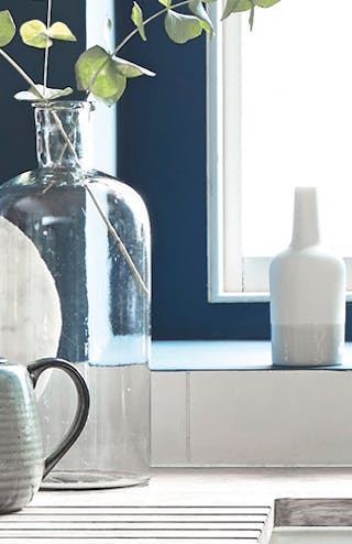 Close up of a kitchen painted in dark blue (Hicks' Blue) with white countertop and sink, in front of a large window.