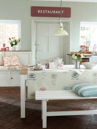 Kitchen diner with walls painted in the grey-green shade 'Pearl Colour', alongside a wooden table with a white bench.