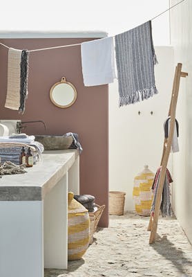 Outside yard space with the left wall painted in neutral red shade 'Nether Red' and the right wall in off-white 'Linen Wash' with a stone worktop and laundry hanging above.