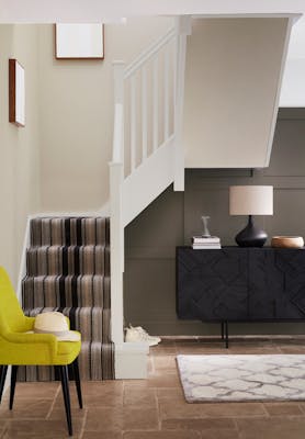 Home entryway with panelling in warm brown shade 'Attic II' and carpeted stairs with pale neutral walls and woodwork.