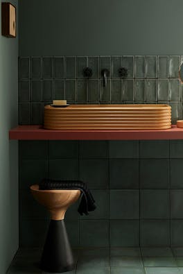 Tiled bathroom painted in grey green shade 'Livid', with contrasting sink, stool and mirror.