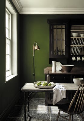 Dining area in deep green shade 'Jewel Beetle' with a wooden table and a rich brown 'Chocolate Color' dresser. 