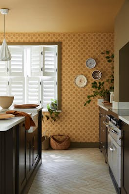 Kitchen space featuring golden yellow small print floral wallpaper (Ditsy Block - Bombolone) with a large window and dark brown cabinets.