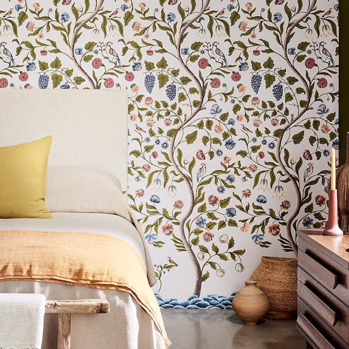 Bedroom featuring white wallpaper comprised of trees in different colors.