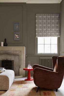 Living space with grey neutral walls (Baluster) alongside a fireplace, armchair and a bright red coffee table.