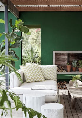 Dark green (Puck) outside living area with panelled wooden floor, cream sofas and a wooden table.