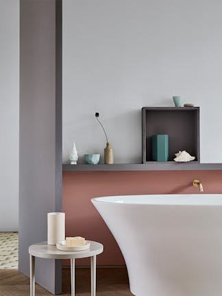 A bathtub in front of a wall with the lower half in a muted pink (Blush) and the upper wall in grey (Gauze - Dark).