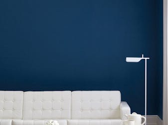 Living room painted in dark blue (Royal Navy) with a white sofa, lamp, table and wooden floor.