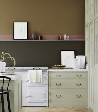 Close-up of a white kitchen counter with a bowl of pears and white artwork leaning on a dark brown (Elysian Ground) wall.