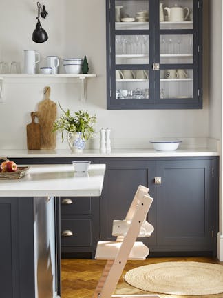 Child's seat placed at a kitchen counter with kitchen units painted in dark blue shade 'Juniper Ash' and the walls in white shade 'Shirting'.