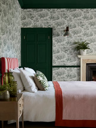 Bedroom with dark green French Toile wallpaper (Lovers' Toile - Puck), dark green (Puck) door and ceiling and white bedding.