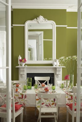 Dining room painted in vibrant green (Citrine) with contrasting off-white woodwork and a dining room table and chairs.