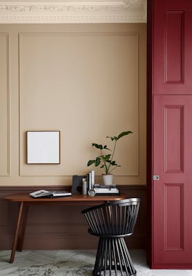 Warm neutral (Castell Pink) home study area with a red (Arras) door next to a wooden desk and chair.  