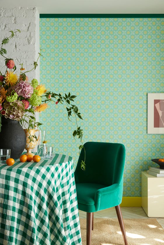 Morning room featuring vibrant green small print floral wallpaper (Ditsy Block - Green Verditer) with a table, green chair and vase of flowers.