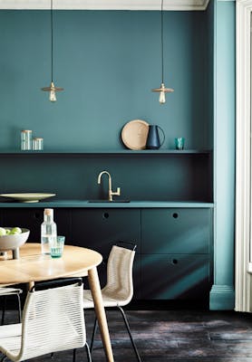 Kitchen painted in blue green (Tea with Florence) and dark green (Harley Green) with a round wooden table and chairs.