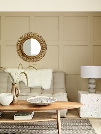 Paneled living space painted in warm neutral 'Travertine' with two sofas and a wooden coffee table.