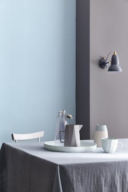 Dining room painted half in blue grey (Arquerite) and half in light blue (Pale Wedgwood) with a table and crockery on top.