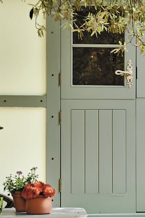 A neutral (Acorn - Mid) shed with muted green (Windmill Lane) wood trim and door.