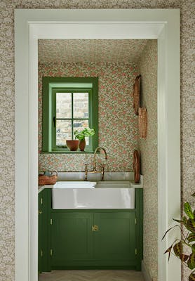 Pantry featuring two colourways of the floral wallpaper 'Spring Flowers' with dark green woodwork and a window above a sink.